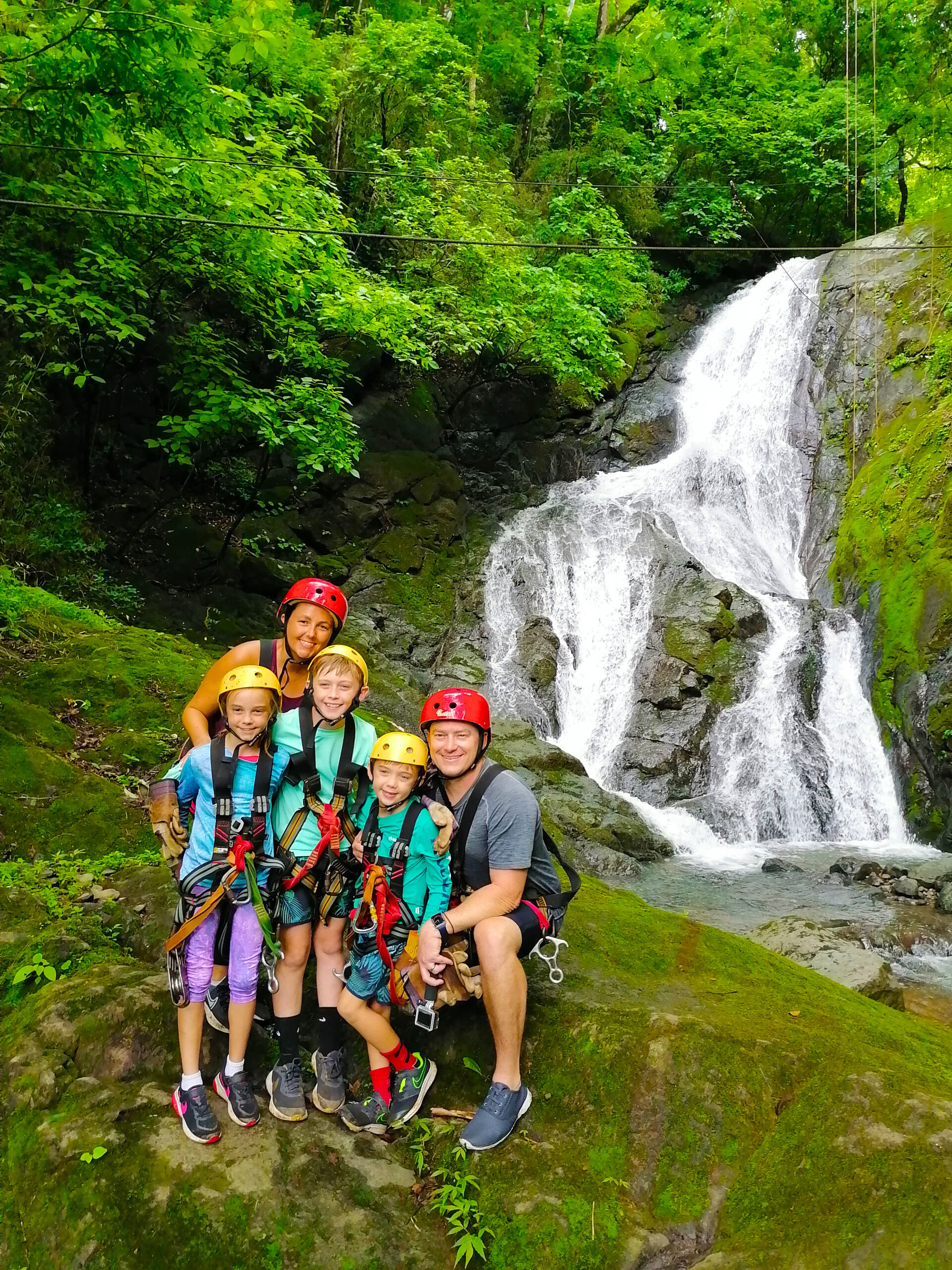 Family smiling before taking Costa Rica's only zipline canopy tour over 11 stunning waterfalls.