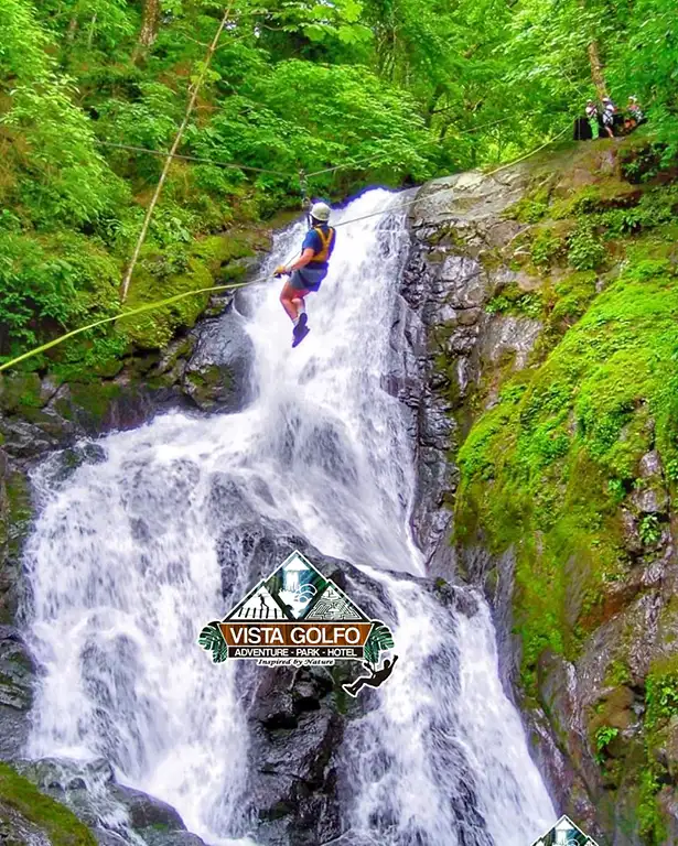 Zip-line-rappel-Costa-Rica Adventurer descending on a zip line over a towering waterfall while guides ensure safety on the platform during Costa Rica’s zip line over 11 waterfalls tour