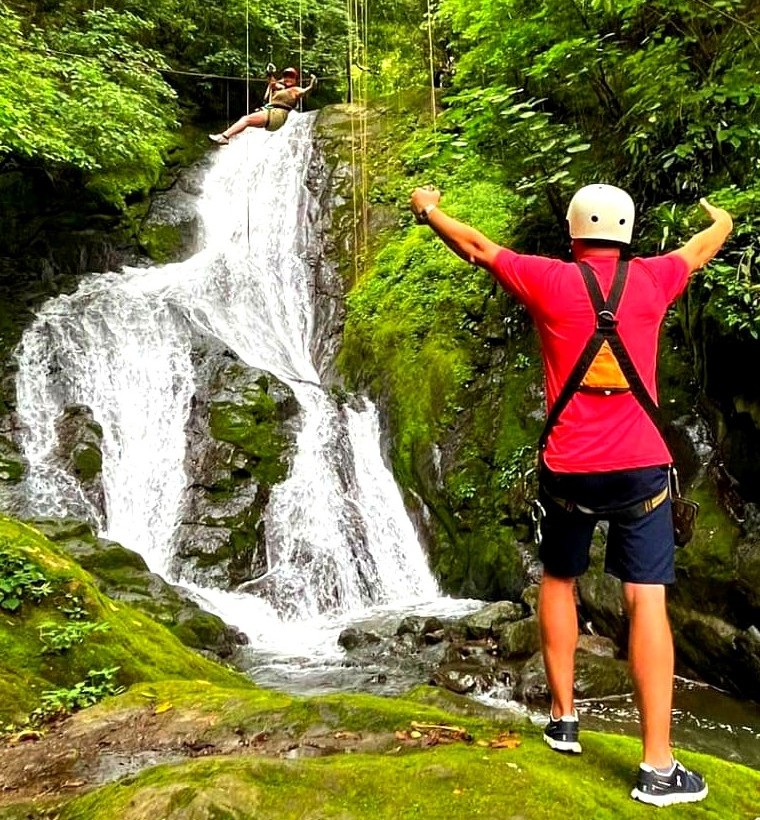 Tourist admiring a majestic rainforest waterfall during a Costa Rica road trip stop between Guanacaste and Jaco.